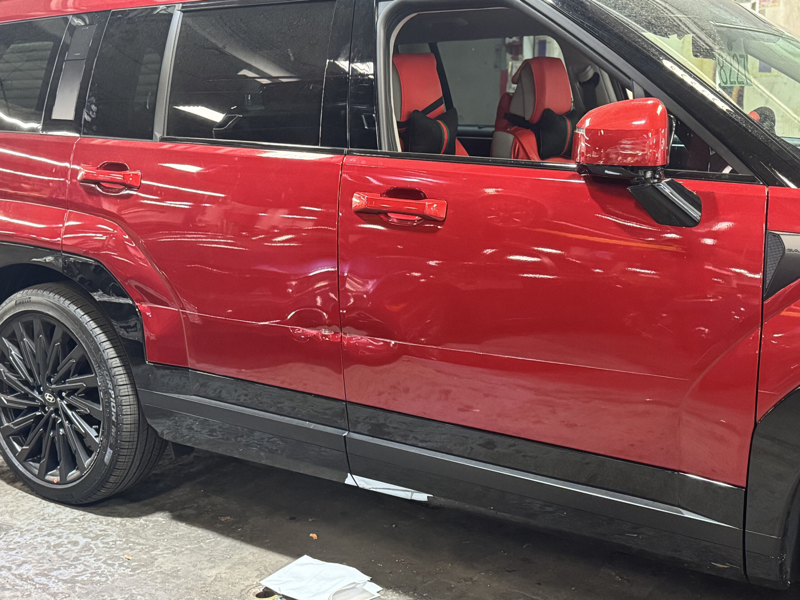 Red SUV with deep dents and scrapes along the passenger-side doors